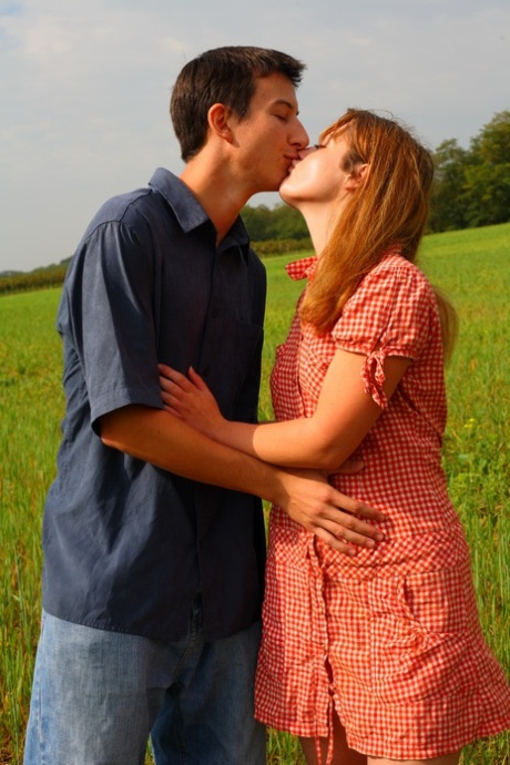 Young couple kiss before having sexual intercourse in a field