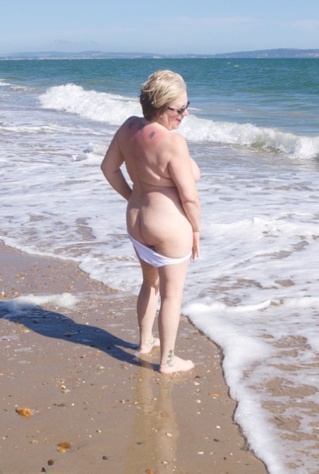 Reife Amateurin Speedy Bee macht sich an einem britischen Strand im Schatten nackt