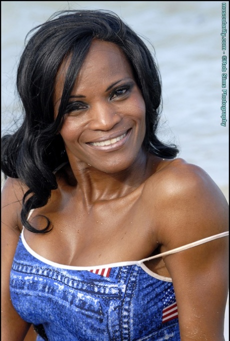 Black bodybuilder Debra Dunn flexes her muscles at the beach in denim attire