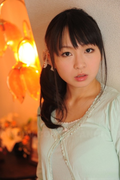 Den fullt påkledde japanske jenta Nozomi Hazuki holder ansiktet fast i det trykte skjørtet.