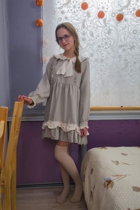 Nerdy meisje doet haar jurk uit en knapt samen met haar bril op haar bed