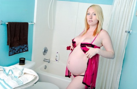 Gravid flicka visar upp sin nakna kropp i badkaret