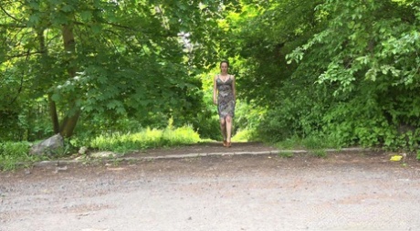Kaukasische meid Valentina Ross zit gehurkt te plassen op een parkeerplaats bij het bos...