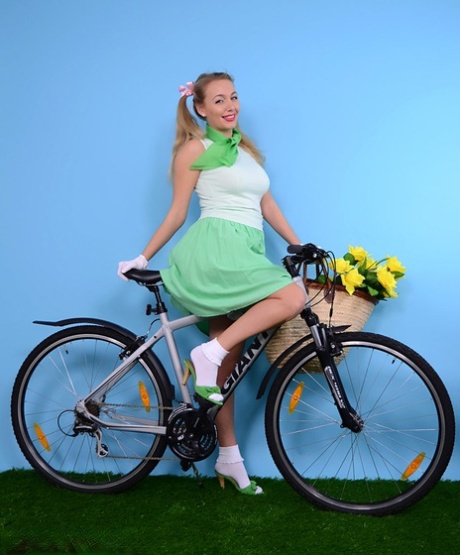 Schattig blondje ontbloot haar stevige tieten op een fiets in witte handschoenen en een tuttig slipje