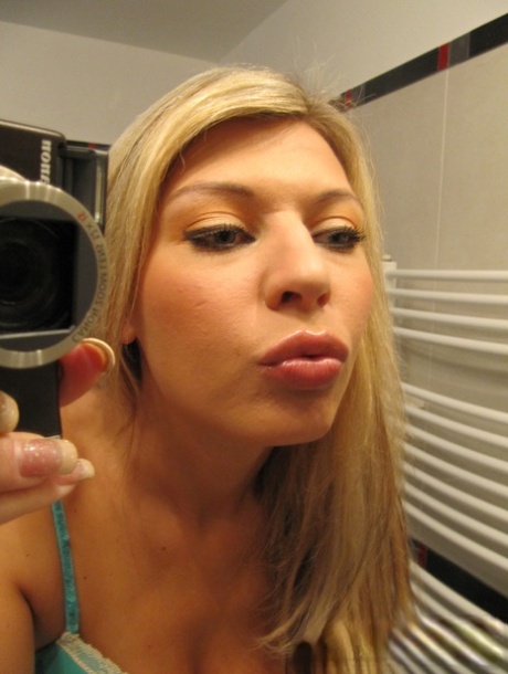 Kurvete babe viser frem de store puppene sine mens hun tar selfies av den nakne kroppen sin.