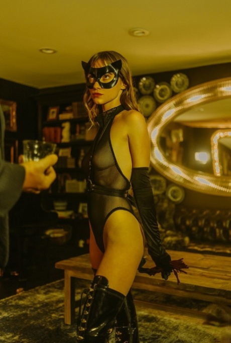 Glamoureuze babe met een masker Nastasia Celeste stript tot haar hoge leren laarzen