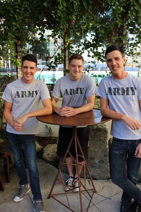 Three army brats pose outdoors before a gay threesome gets underway