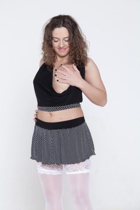Dominique, de cabelo encaracolado, fica só com as meias brancas e abre a sua vulva peluda